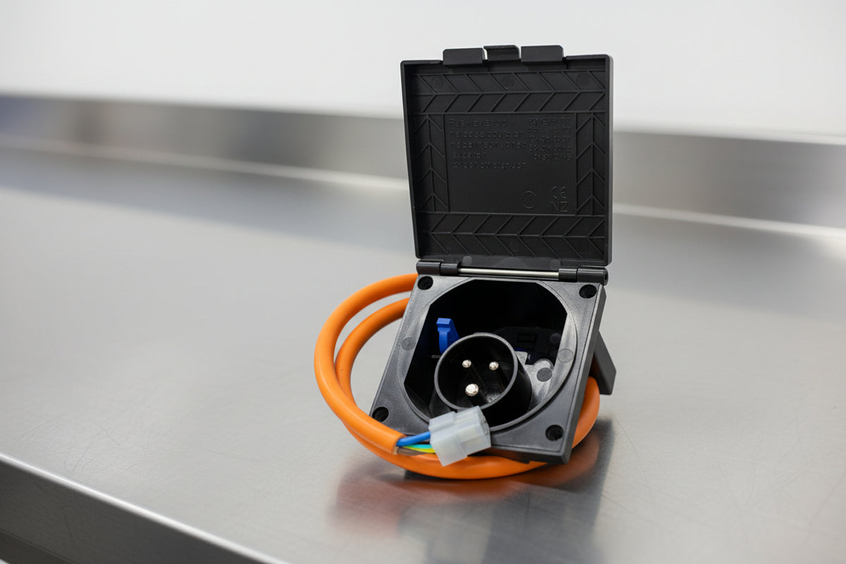 Opened black power inlet box with orange cable and plug connectors