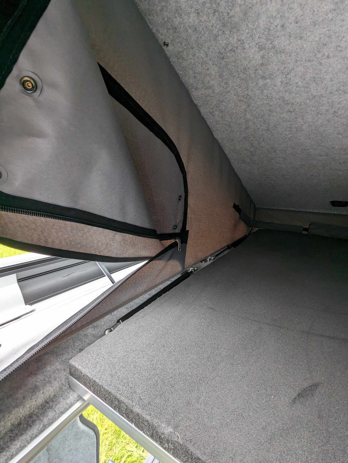 Camper van roof bed platform with gray fabric mattress panel
