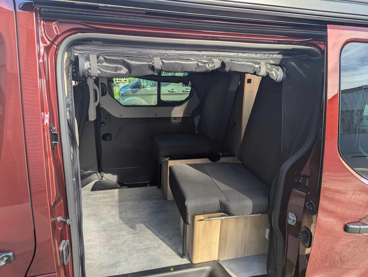 Camper van mosquito net installed over rear door, black mesh view into seating area