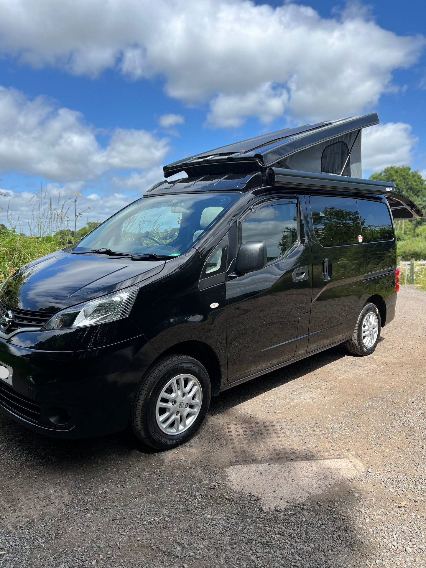 Black campervan conversion with raised pop-top roof and alloy wheels