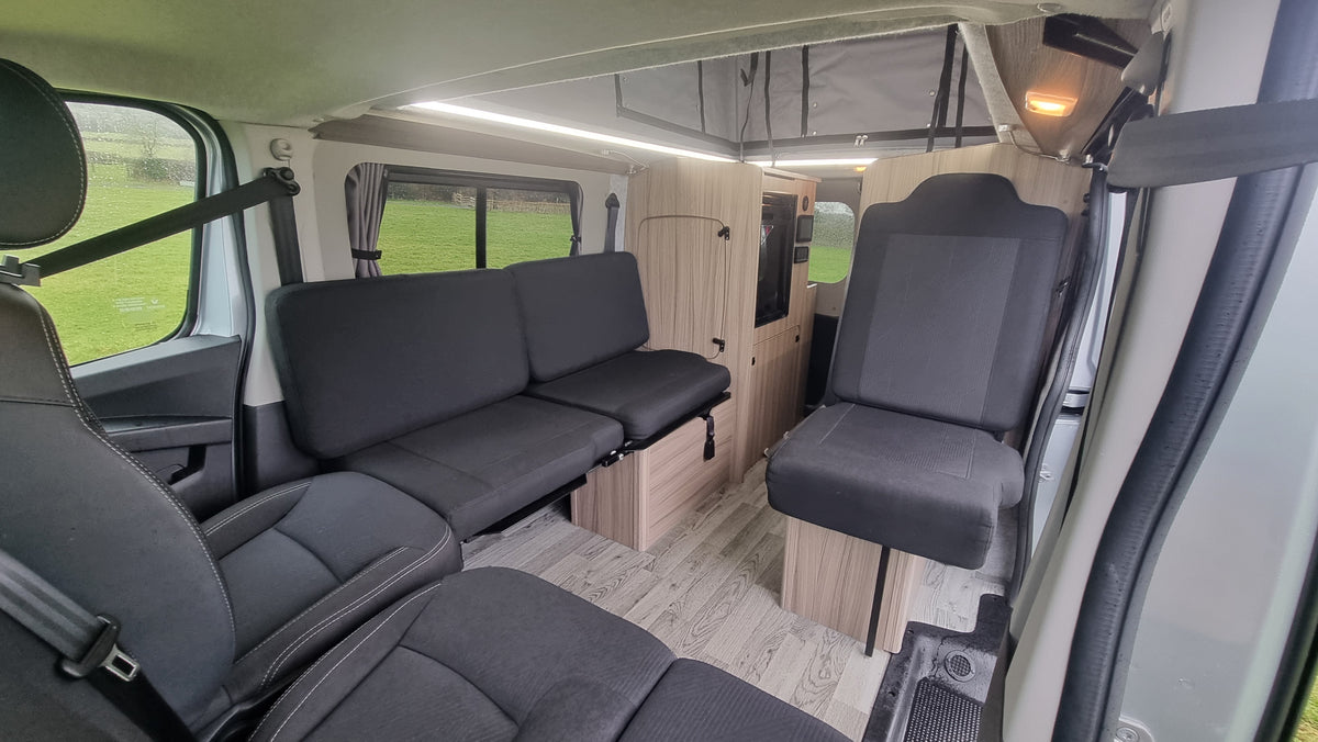 Motorhome rear lounge with gray sofa seats and light wood table