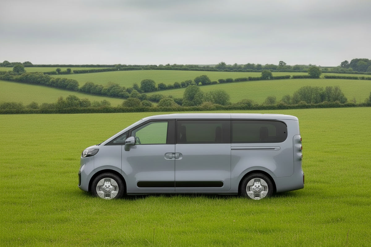 White campervan conversion in full side view, parked outdoors in a green field.