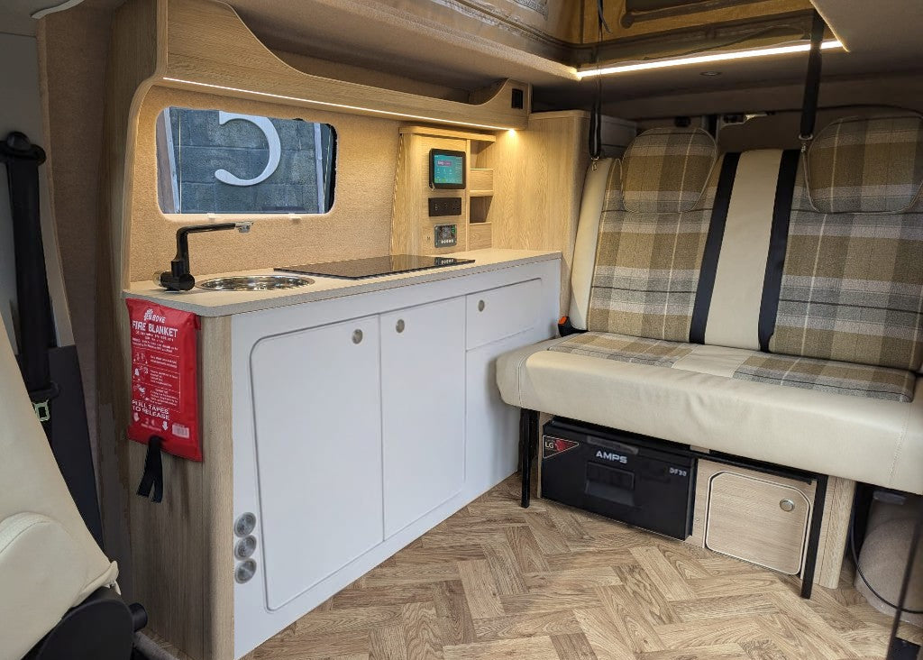 maxus edeliver 3 Micro campervan interior with white kitchen cabinets and cushioned side bench