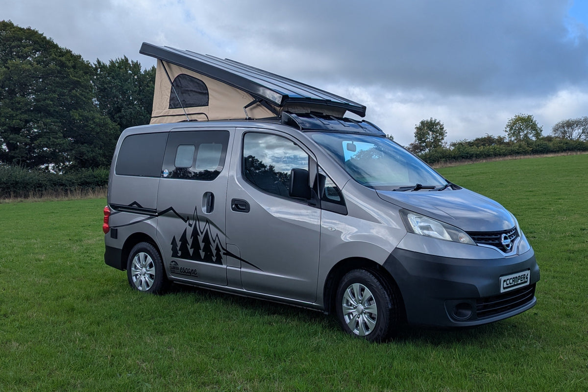 Silver Nissan micro campervan with pop-top tent and graphic side decals