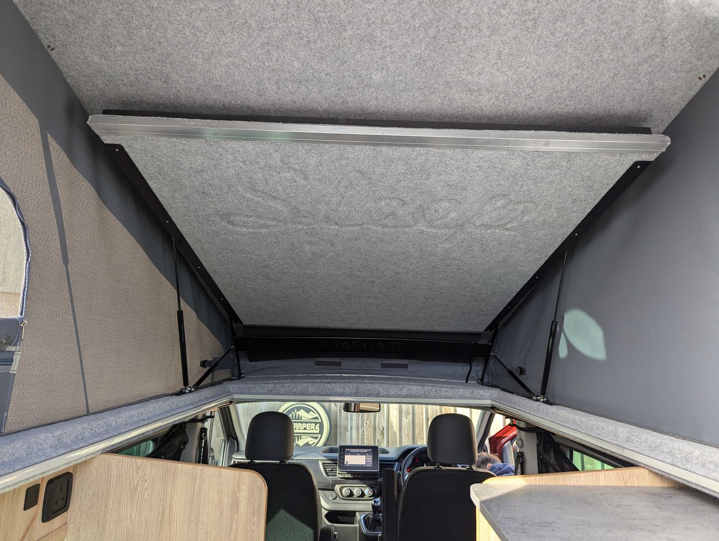 Raised roof bed panel and side support frame opened over vehicle ceiling