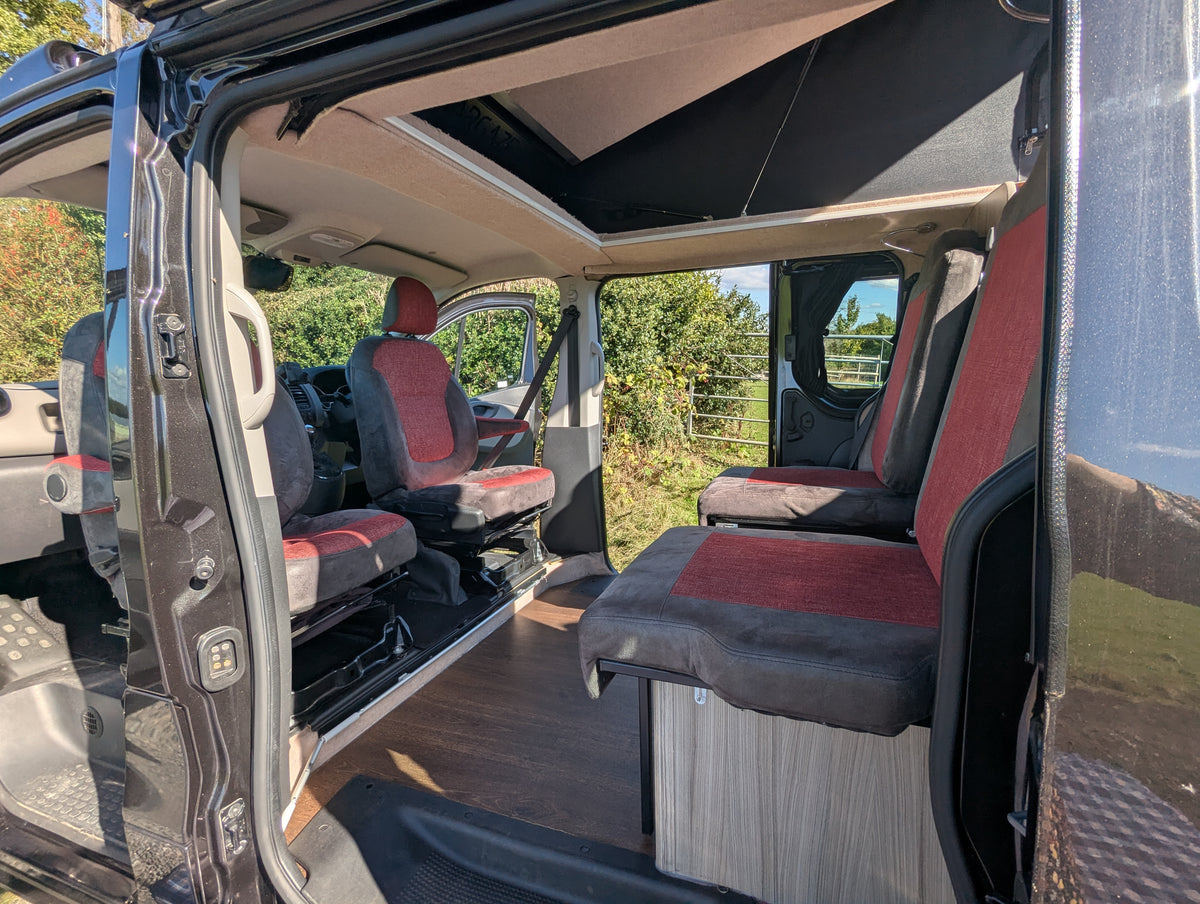 Campervan open side door showing front seats and cushioned rear bed area