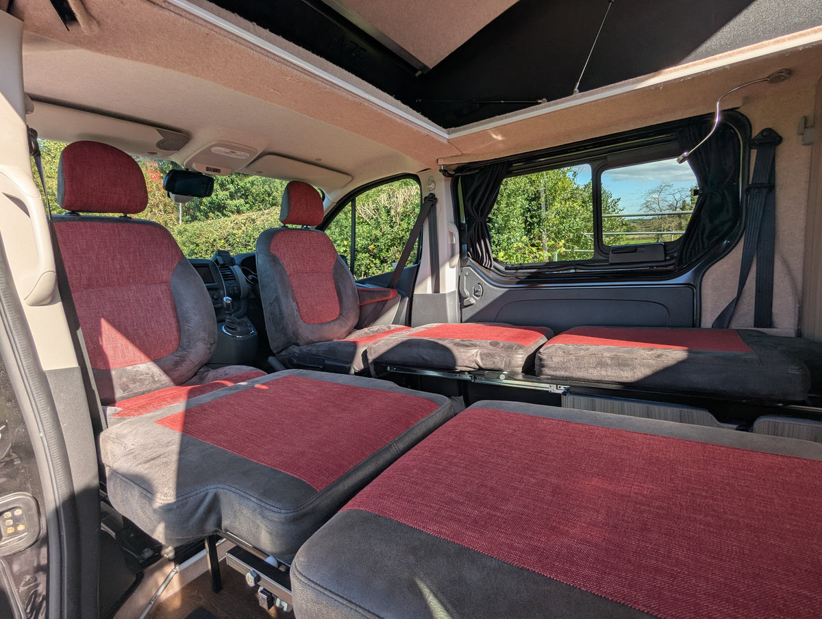 Campervan bench seating with maroon cushions and fold-down table for dining