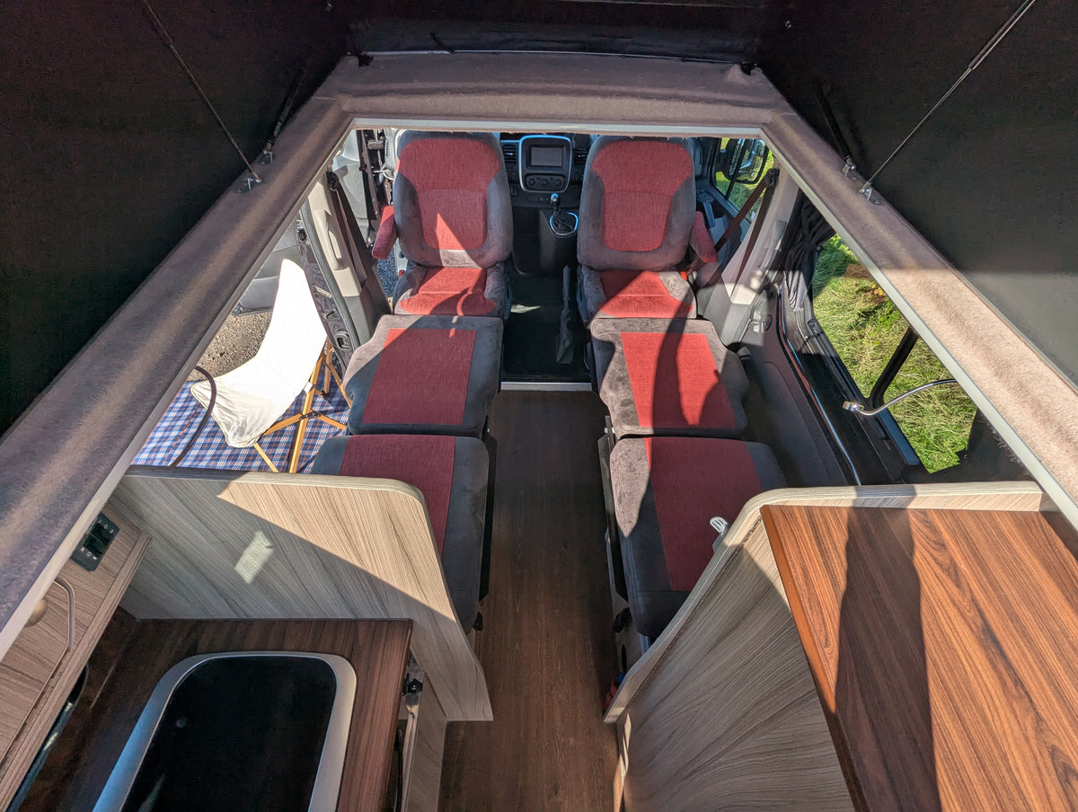 Campervan sleeping layout with red cushions, wood cabinetry, and twin beds