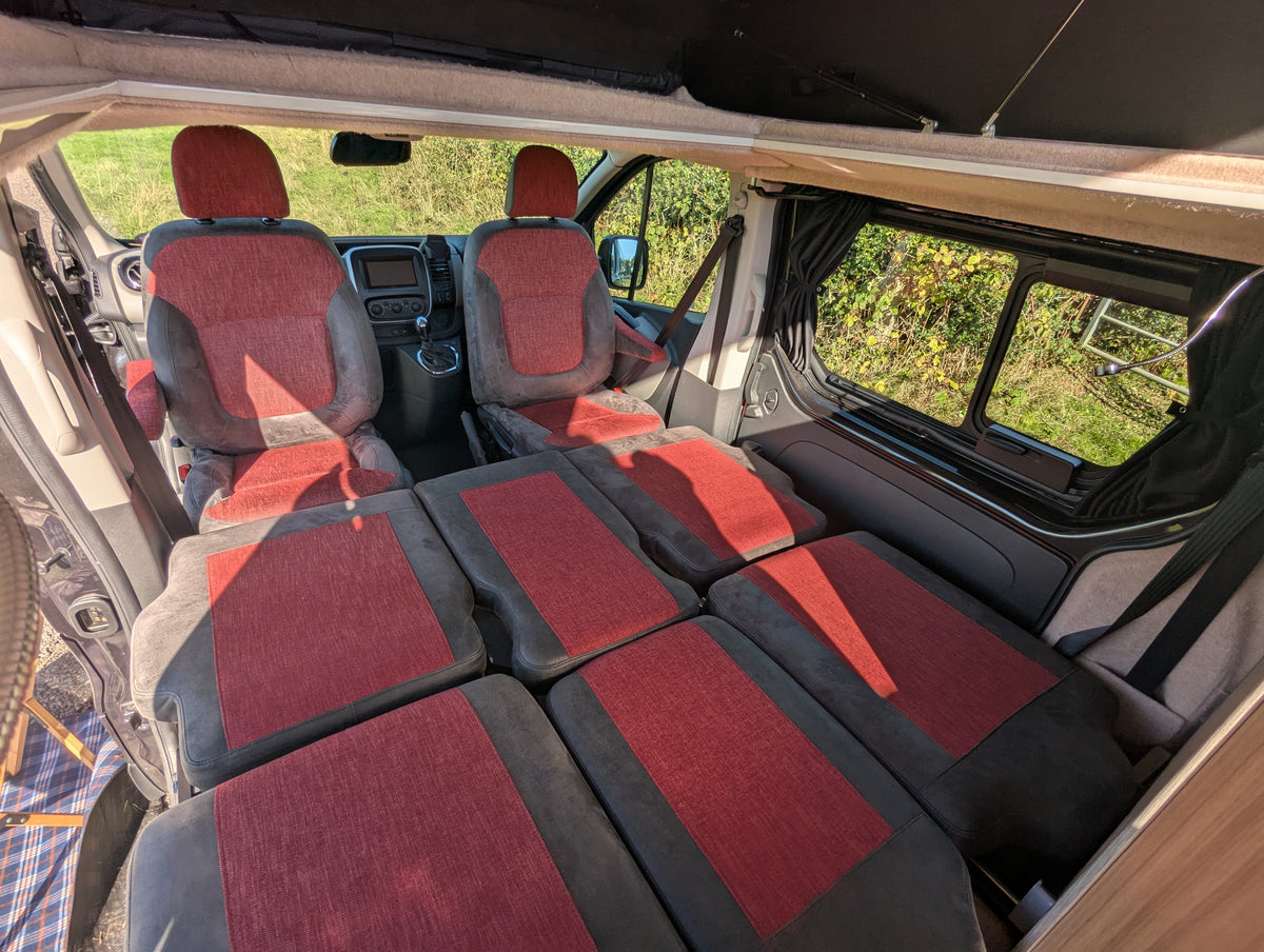 Campervan convertible bed with maroon and gray cushioned panels arranged lengthwise