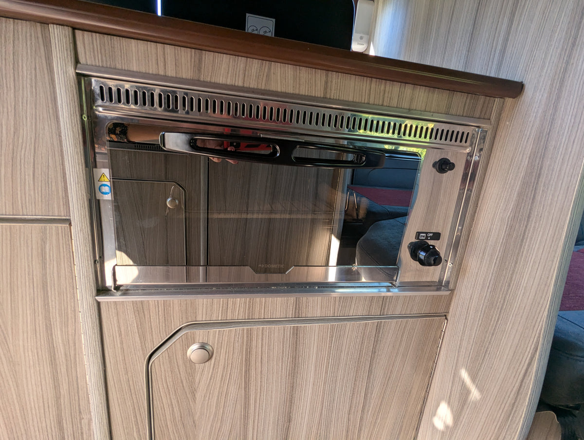 Campervan kitchen cabinet with built-in sink area and metal vent panel
