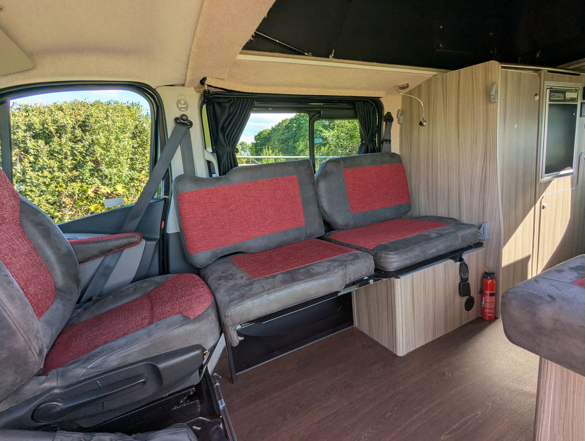 Campervan seating area with red-and-gray cushions and bench seating