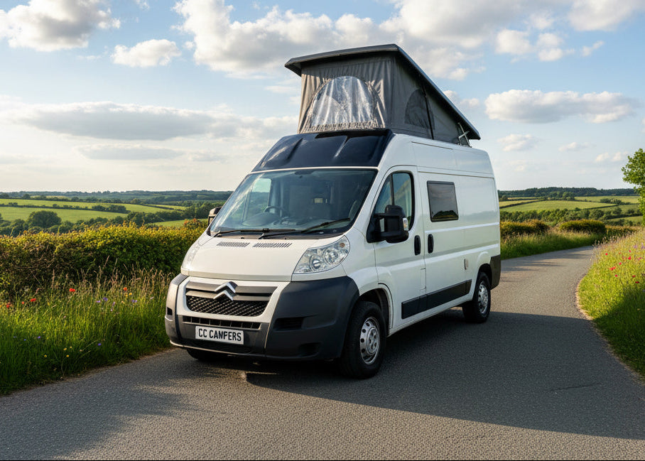 White camper van with raised pop-top roof and front cab
