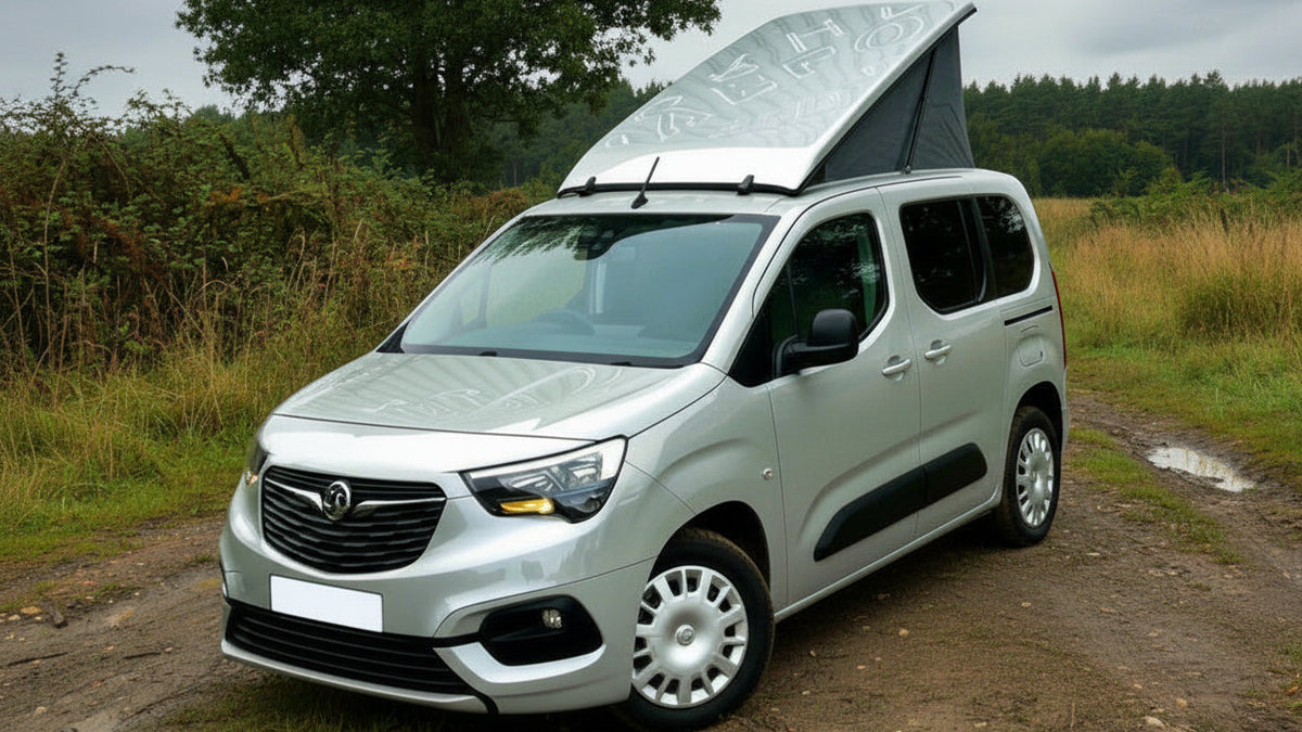 Light gray camper van with pop-top roof raised, black canvas tent over cabin.