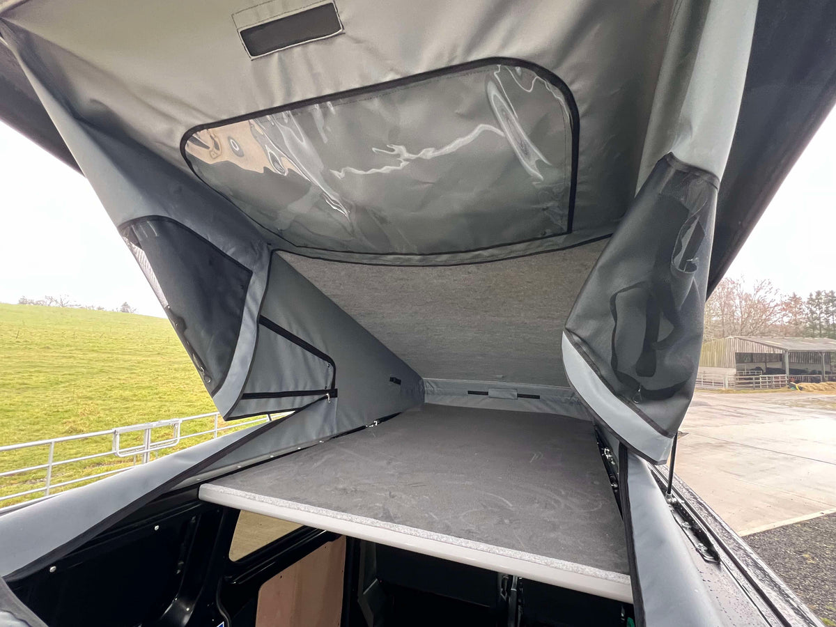 Pop-top roof interior with fabric liner and metal support arms over the opening.