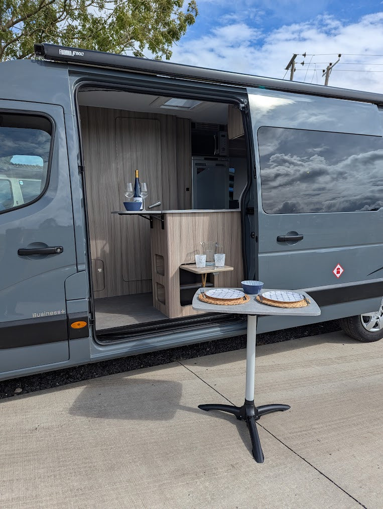 Gray van with open door revealing a small kitchen setup on a concrete surface.