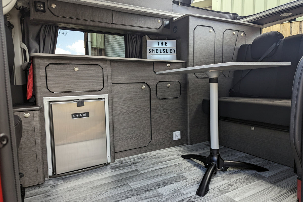 Campervan side-kitchen interior with dark cabinets, sink area, and countertop