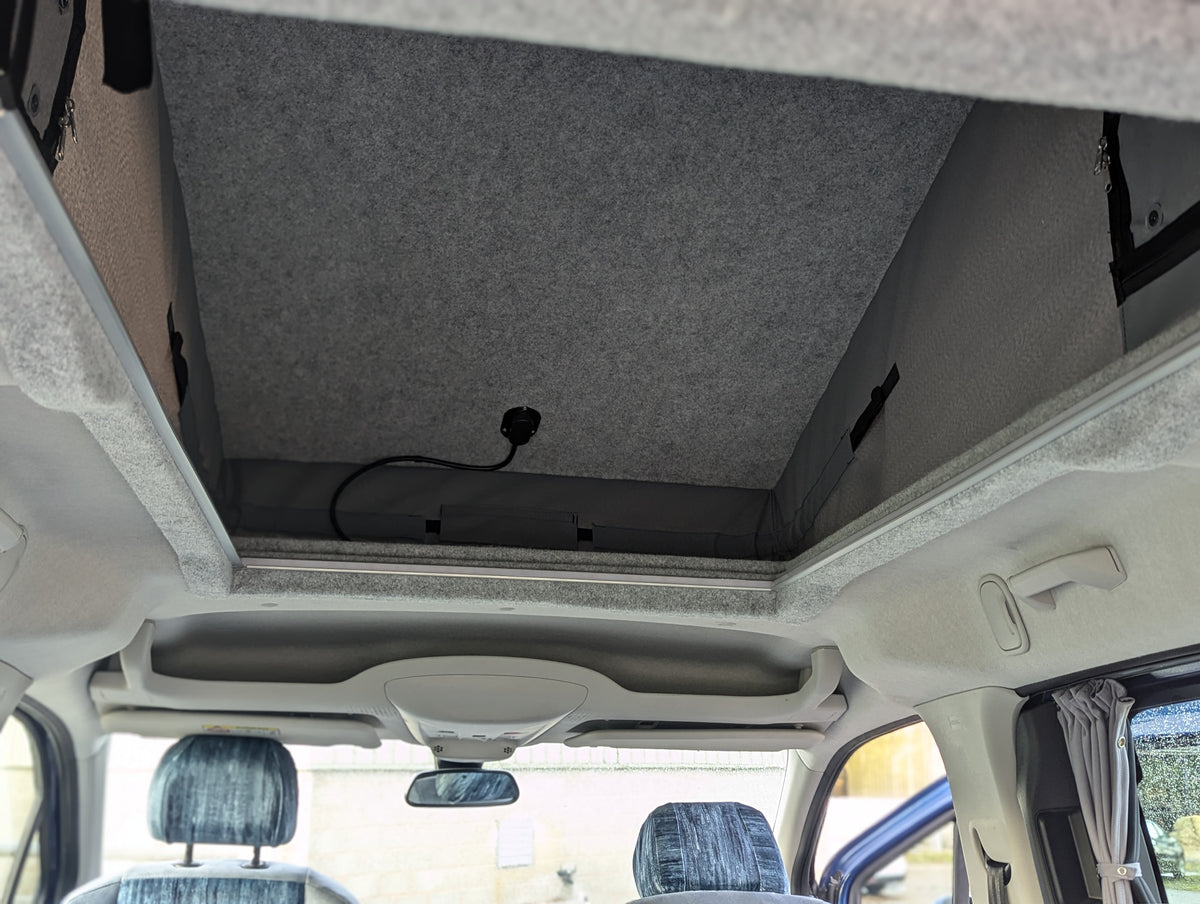 Campervan headliner with front cabin view and blue patterned seat covers