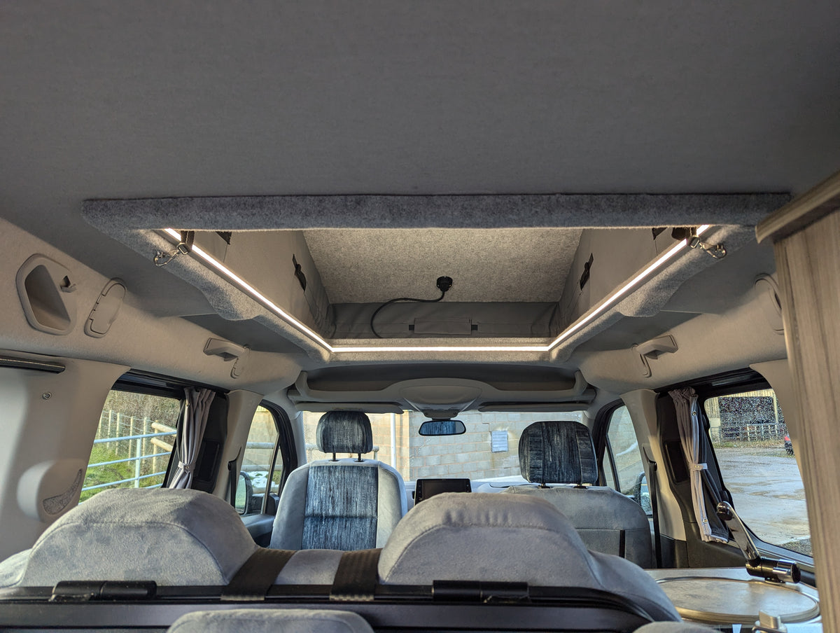Campervan ceiling with overhead panel and skylight above front seats