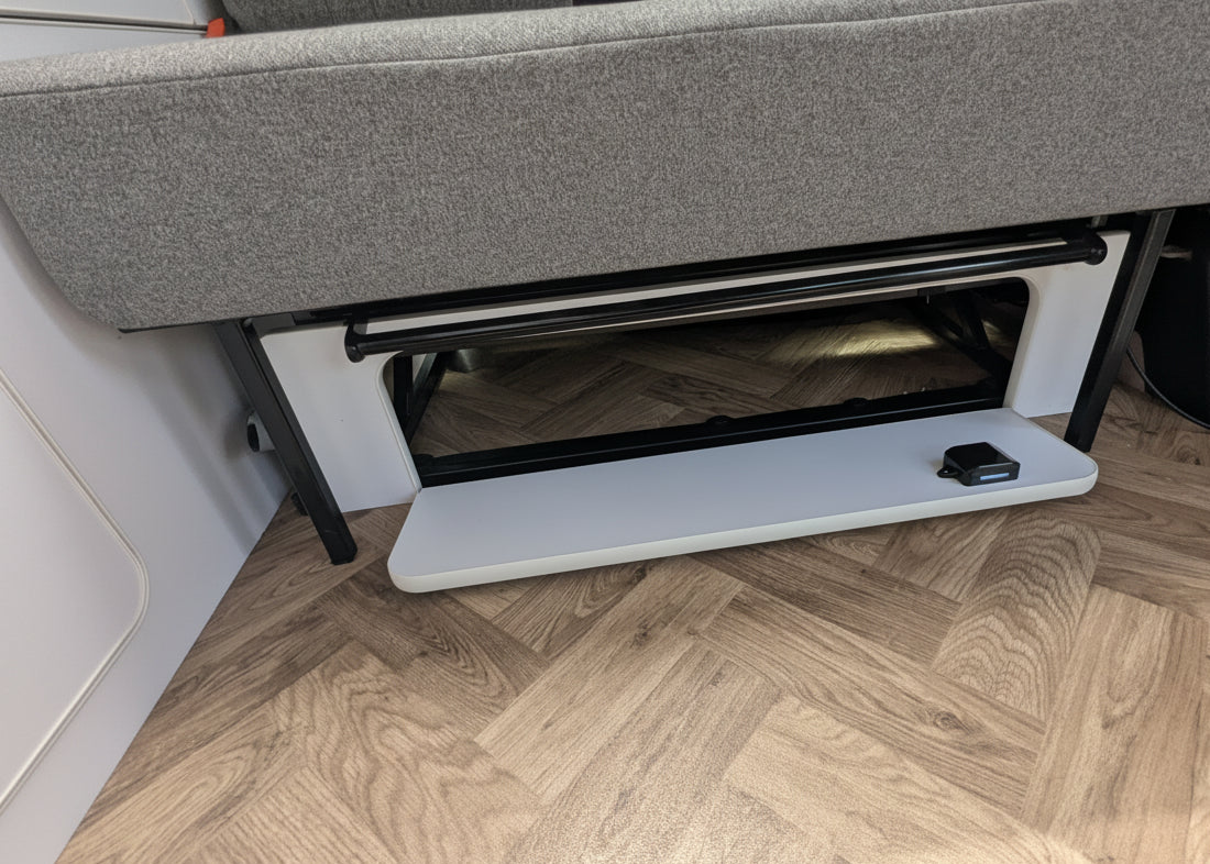 Close-up of vw id buzz seat with a storage compartment underneath, set on a light wood herringbone floor.