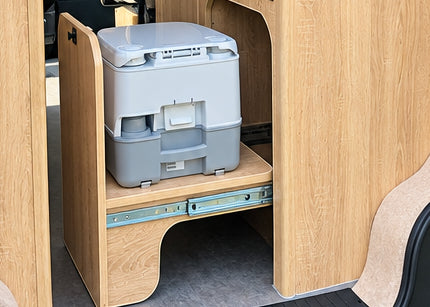 Close-up of the smooth integrated pull-out slide mechanism holding a portable chemical toilet inside the lower cabinet of the Kia PV5 Witley campervan.