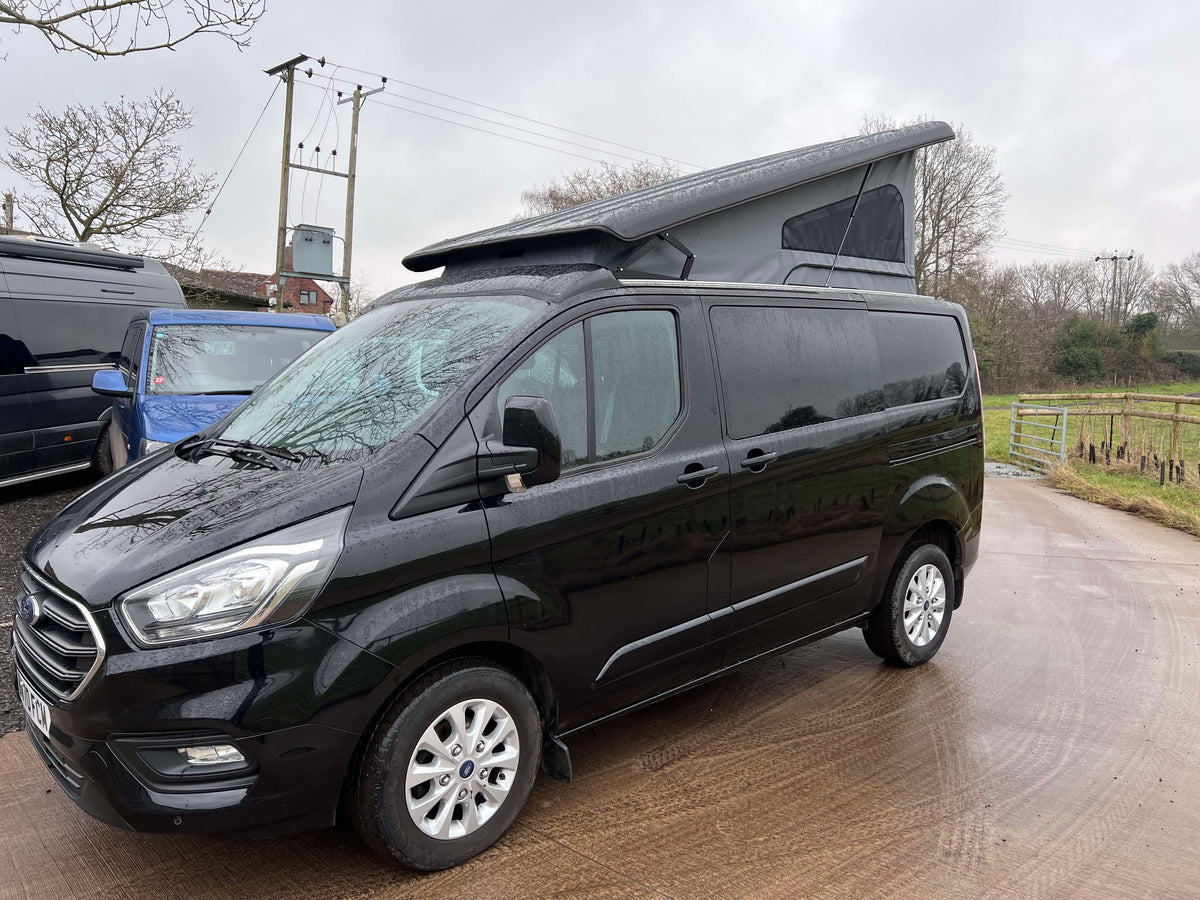 Dark Ford Transit Custom van with pop-top roof closed, side profile view