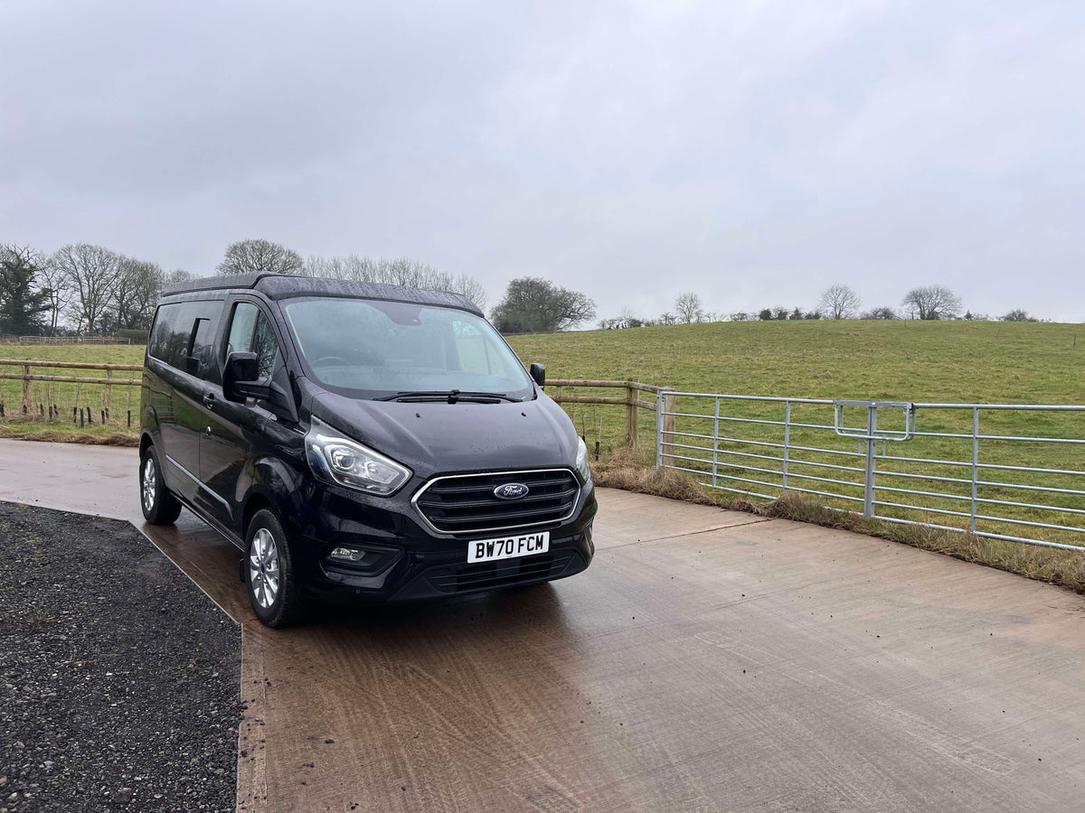 Black Ford Transit Custom van with pop-top roof closed and roof profile visible.