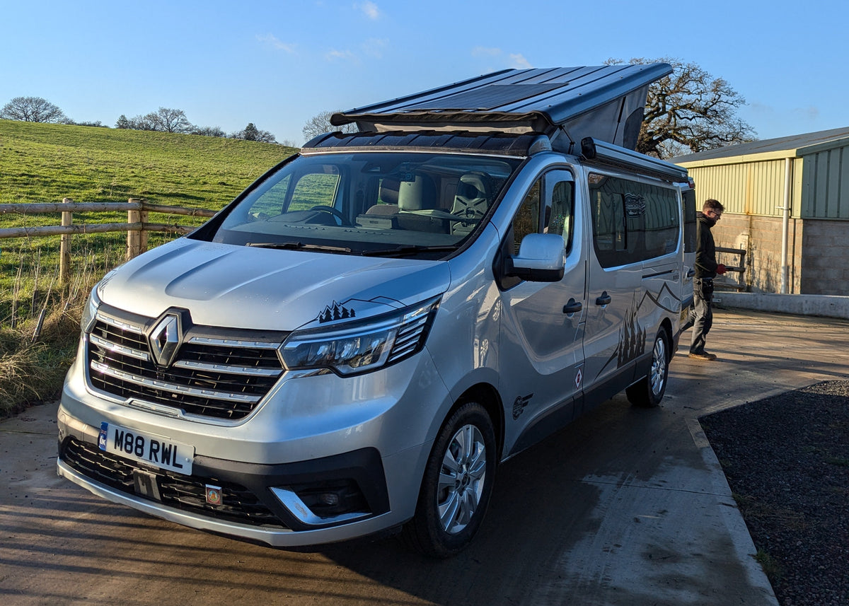 Light blue campervan conversion with roof rack, front and side view