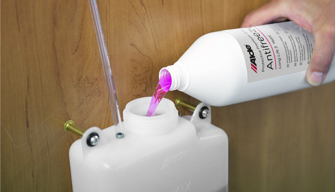 Purple coolant replacement fluid being poured into a white tank