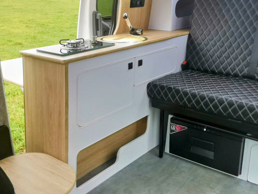Interior of a camper van with kitchen setup and storage area.