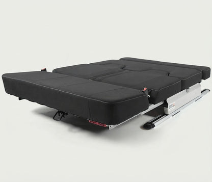 A black convertible sofa bed or travel bed frame with a silver metal base, shown partially unfolded on a light gray studio background.