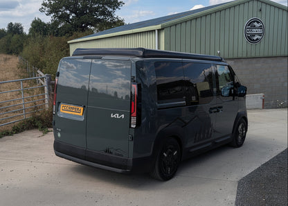 Rear view of dark green camper pop-top on Kia van with roof closed