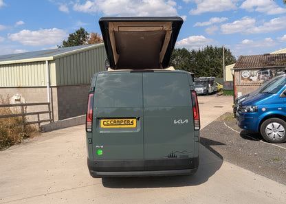 Kia van with pop-top roof raised, rear view showing open roof canvas