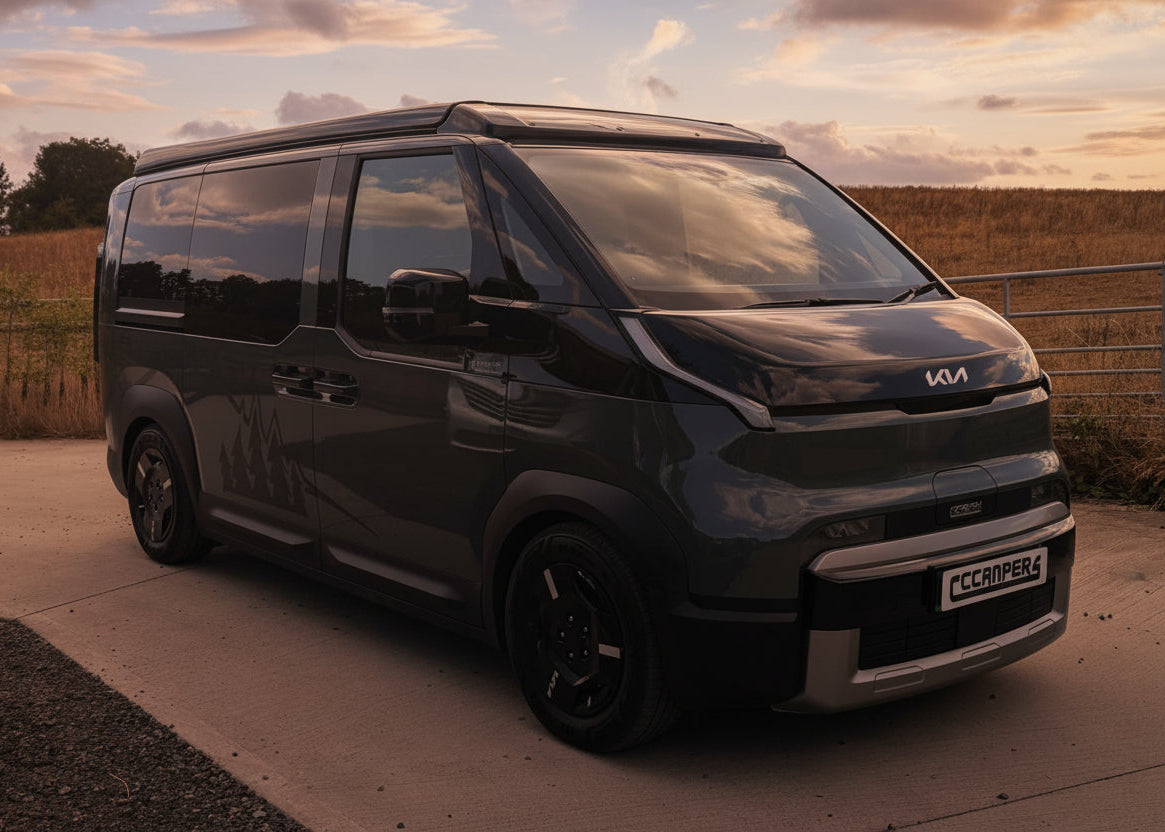 Dark Kia van with pop-top roof closed, front three-quarter view outdoors
