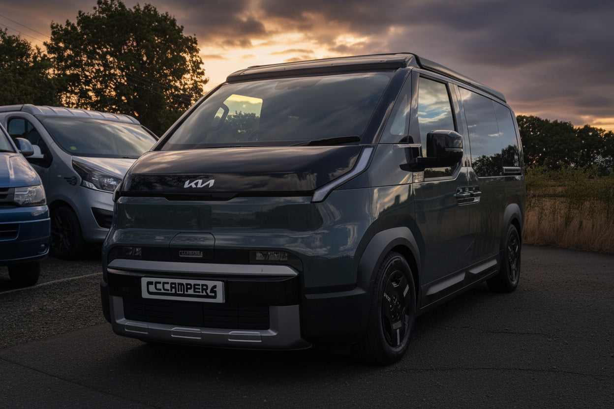 Dark Kia van with pop-top roof raised, front view at dusk