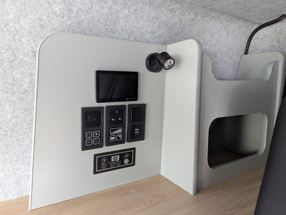 Gray electronic device with control panel on a wooden surface against a gray wall.