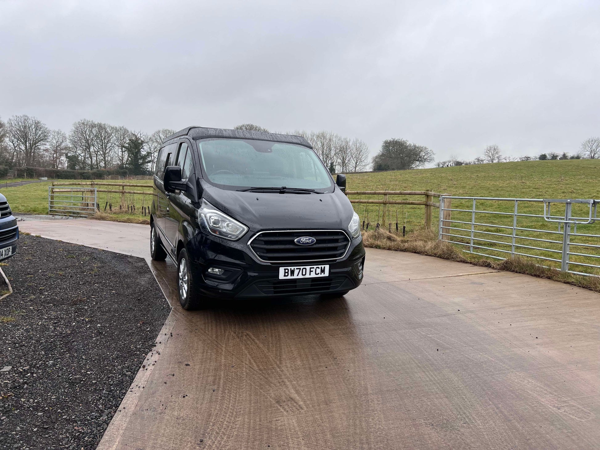 Black Ford van parked on a driveway with a rural landscape in the background