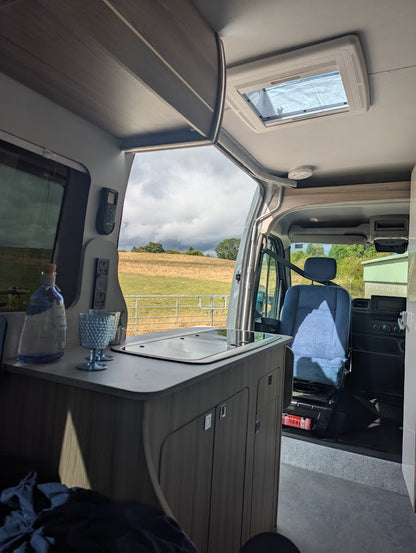 Interior of a camper van with a view of a field through the windshield.