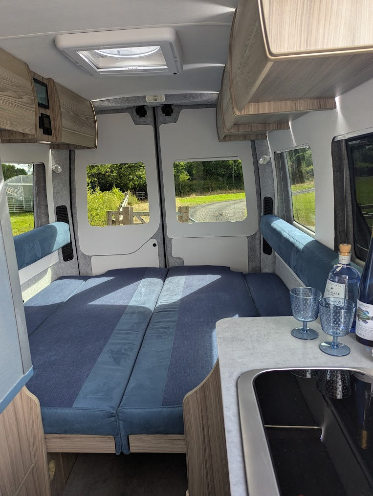Interior of a compact vehicle with sleeping area and kitchenette.