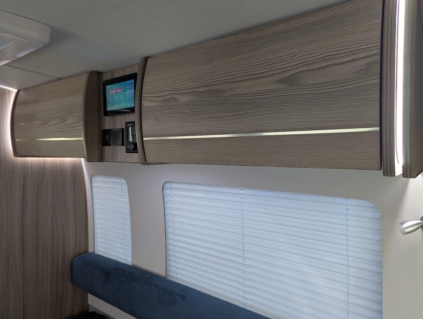 Interior of a vehicle with wooden paneling, bench seat, and small screen display.