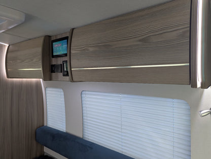 Interior of a vehicle with wooden paneling, bench seat, and small screen display.