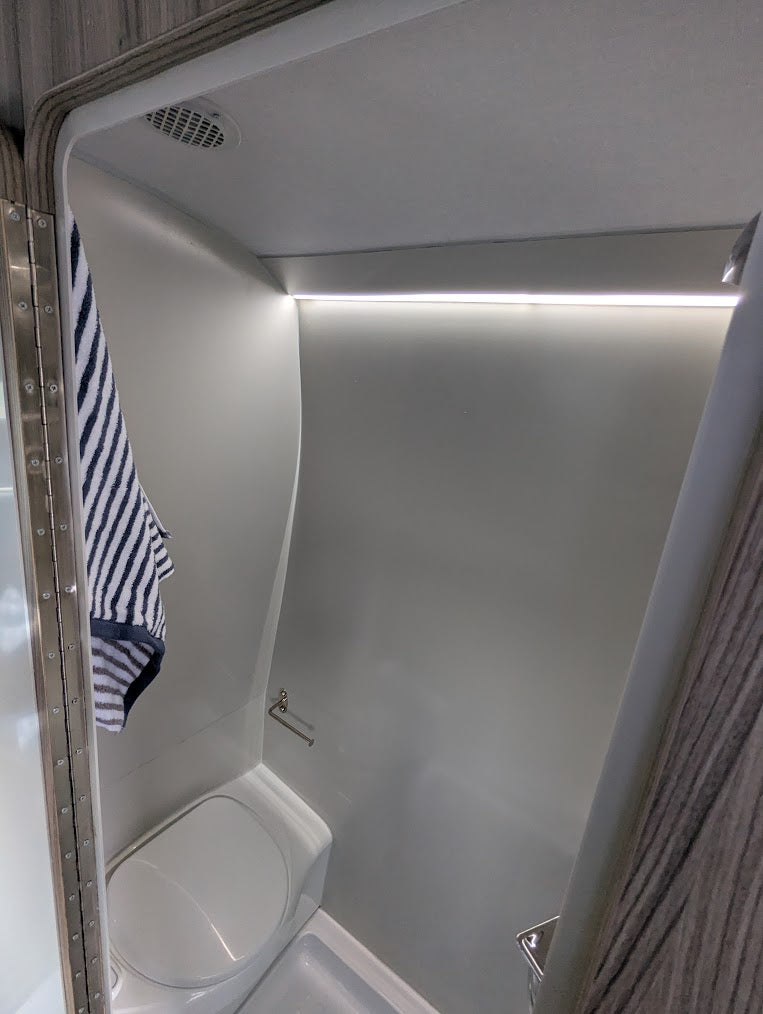 Small enclosed shower with a striped towel hanging on the left side.