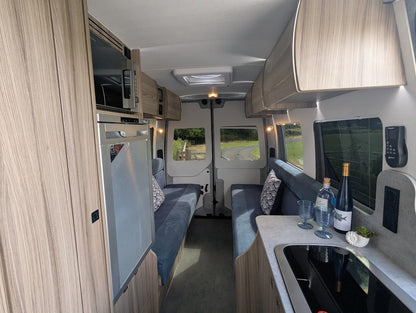 Modern RV interior with kitchenette, seating area, and entertainment system.