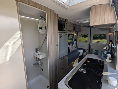 Interior of a compact living space with kitchenette, shower, and seating area.