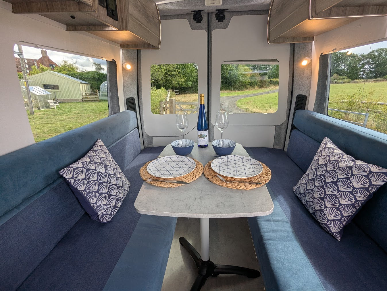 Interior of a camper van with blue couch, small table, and decorative pillows.