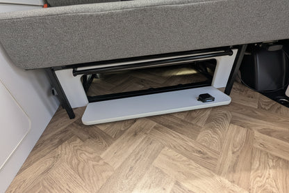 Close-up of vw id buzz seat with a storage compartment underneath, set on a light wood herringbone floor.