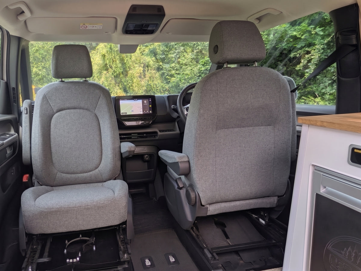 Campervan front cabin with two grey seats, dashboard, and infotainment screen