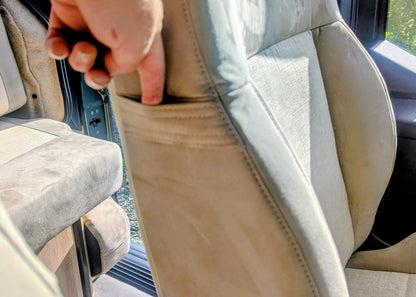Close-up interaction showing the integrated storage pocket on the back of the front passenger seat inside the Kia PV5 Witley campervan.