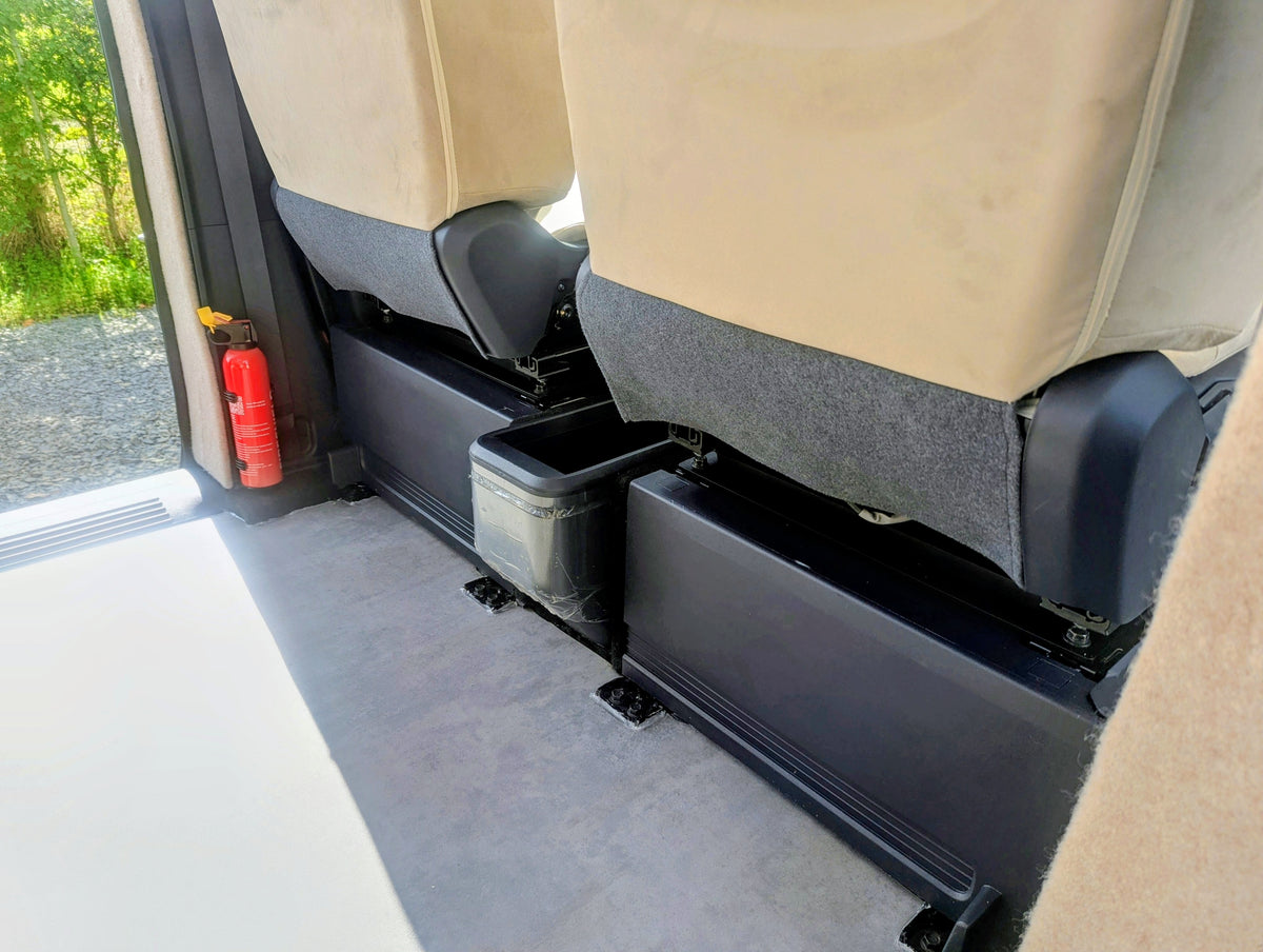 Interior shot of the rear passenger seating bases and floor mounting rails with an emergency fire extinguisher mounted nearby in the Kia PV5 Witley.