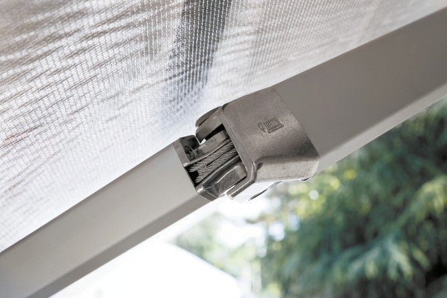 Close-up of a F45s mesh canopy attachment bracket secured to a white frame, with blurred green foliage in the background.