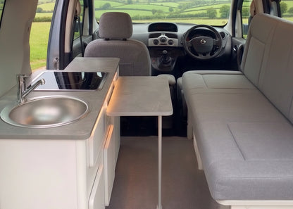 Renault Kangoo panel van campervan conversion interior showing side kitchen with sink and hob, folding table, and upholstered side bench seat — custom-built by CCCAMPERS, Worcestershire